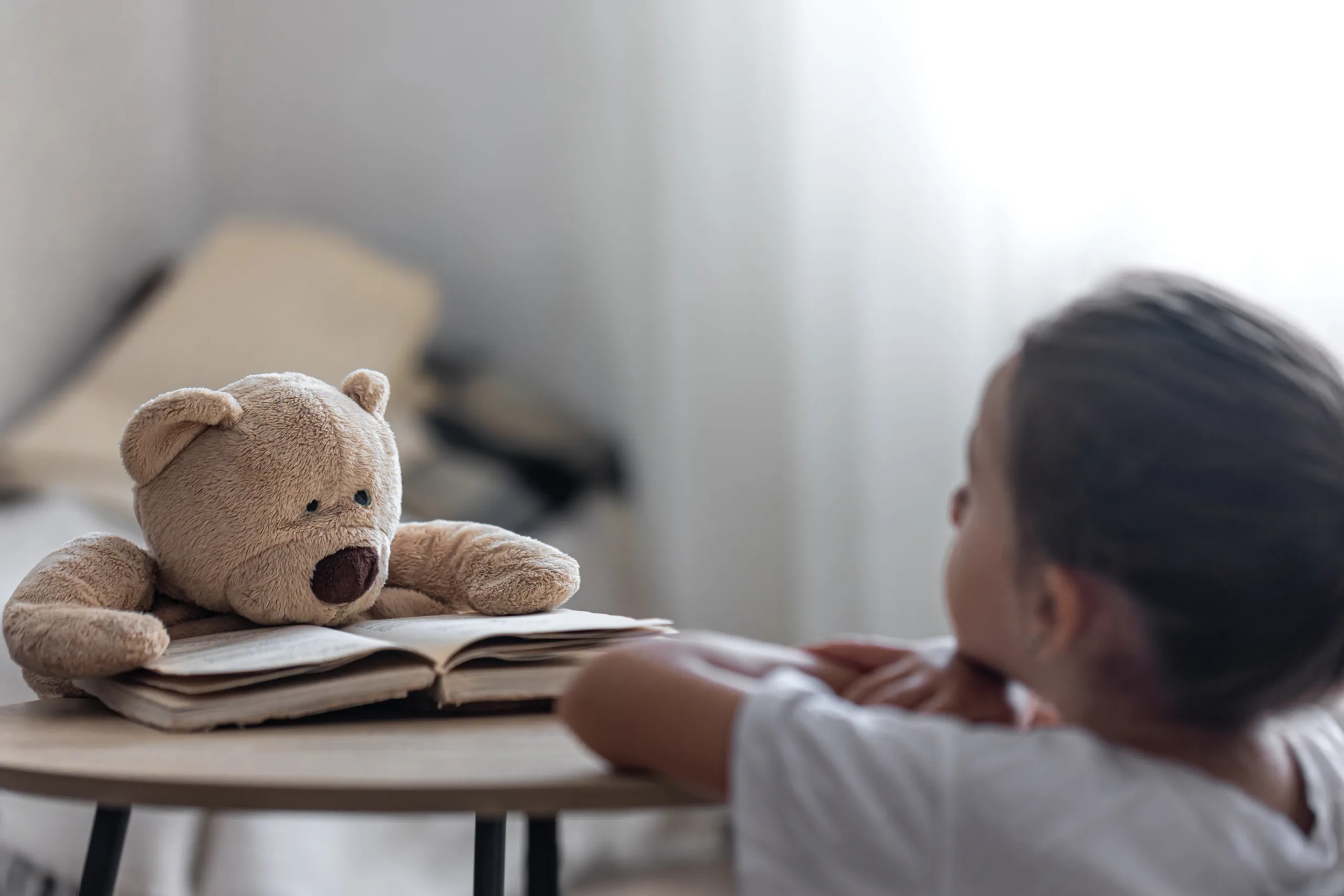 Niña jugando con oso que está leyendo.